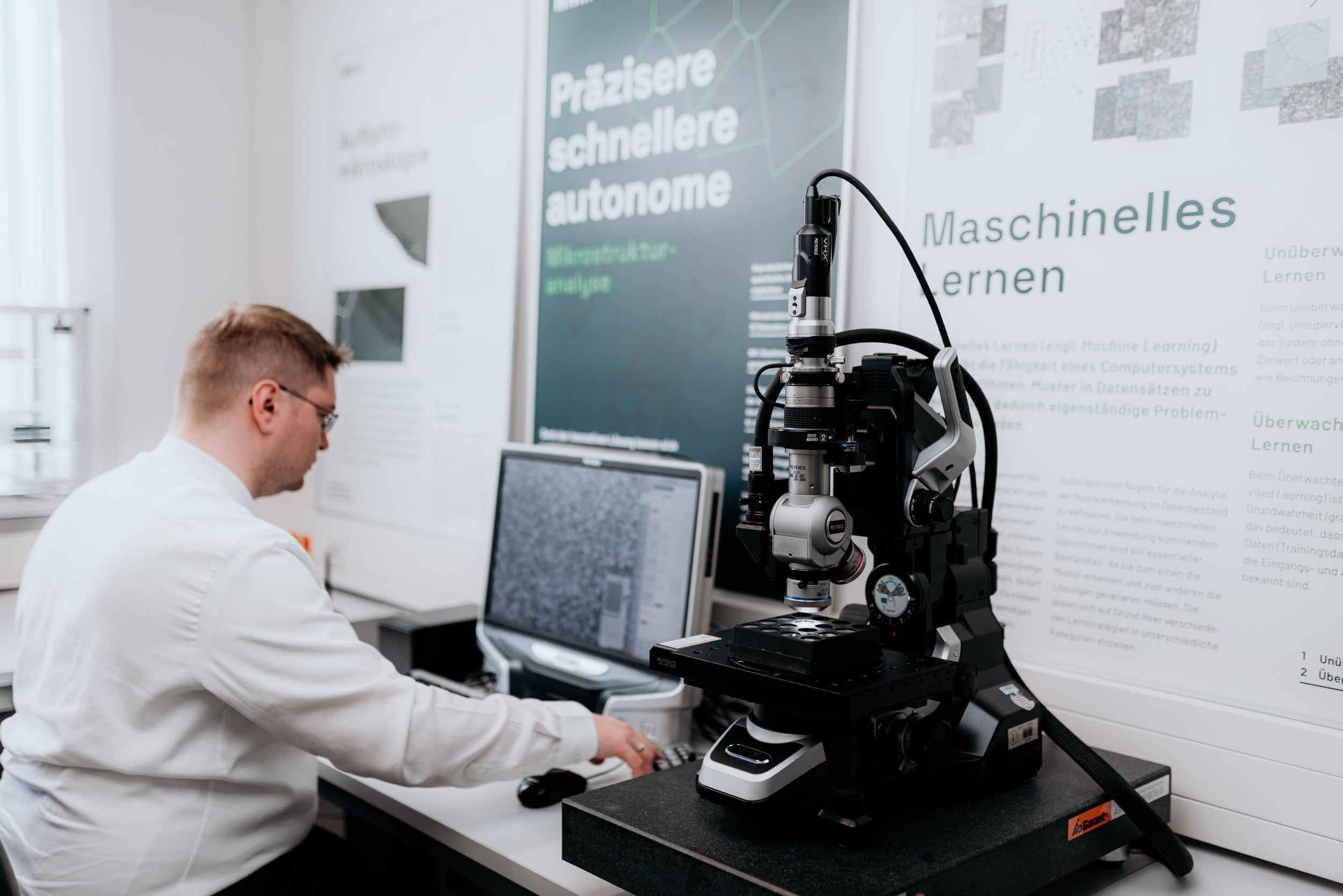 Man sitting next to microscope analysis microstructure.